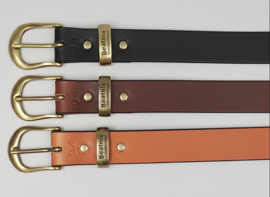 Three leather belts with brass buckles on a light gray background